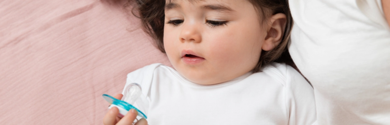 Bébé tenant une sucette - Laboratoires Gilbert